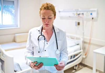 Mature female doctor reading clipboard while working in hospital